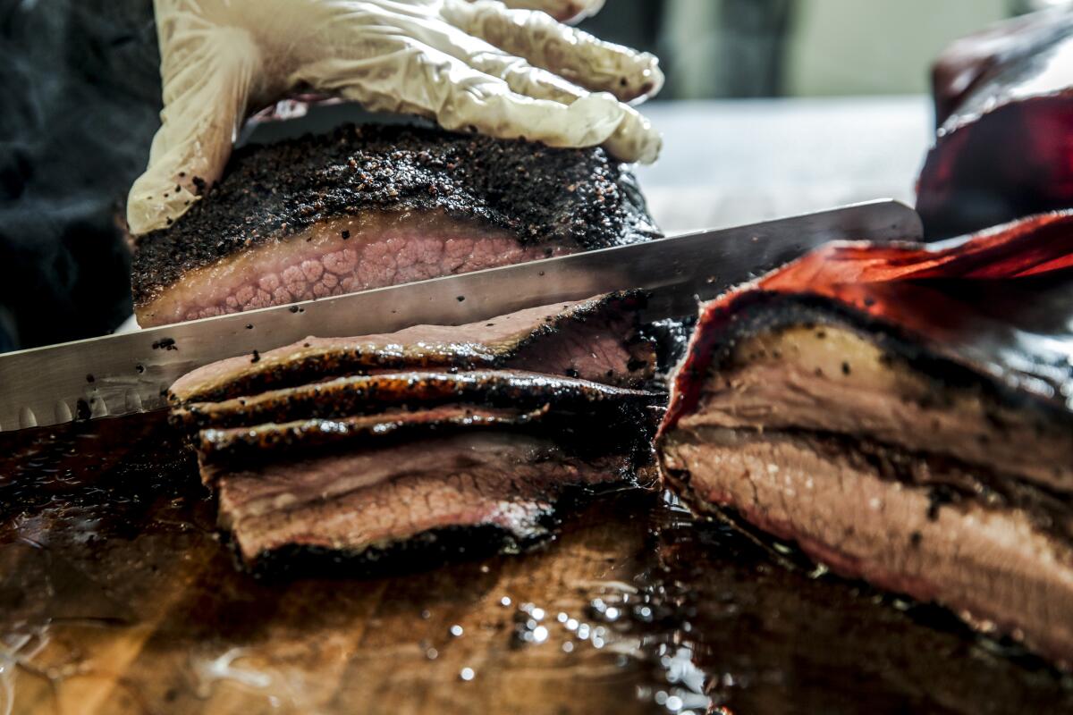 Charred brisket with a knife slicing through it.