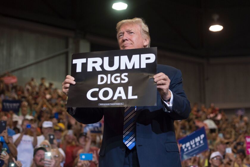 President Trump holds up a "Trump Digs Coal" sign as he arrives to speak during a Make America Great Again Rally at Big Sandy Superstore Arena in Huntington, West Virginia, August 3, 2017.