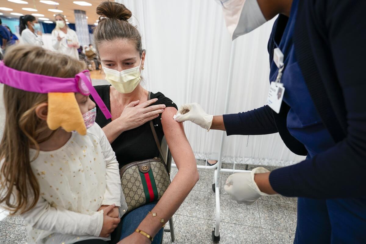 Mosque member Asie Late's granddaughter Emma watches as a Northwell Health registered nurse inoculates her with the Johnson & Johnson COVID-19 vaccine at a pop up vaccination site inside the Albanian Islamic Cultural Center, Thursday, April 8, 2021, in the Staten Island borough of New York. (AP Photo/Mary Altaffer)