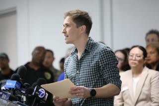 A man speaking while holding a folder