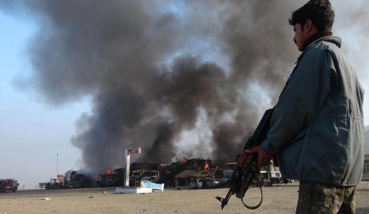 Afghan security personnel stand alert near burning vehicles Wednesday in the Torkham area, near the border with Pakistan in Afghanistan's Nangarhar province.