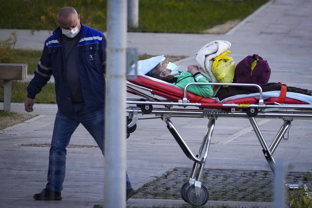 A medical worker carries a patient suspected of having coronavirus on a stretcher at a hospital in Kommunarka, outside Moscow, Russia, Monday, Oct. 11, 2021. Russia's daily coronavirus infections and deaths are hovering near all-time highs amid a laggard vaccination rate and the Kremlin's reluctance to toughen restrictions. Russia's state coronavirus task force reported 29,409 new confirmed cases Monday. That's the highest number since the start of the year and just slightly lower than the pandemic record reached in December. (AP Photo/Alexander Zemlianichenko)