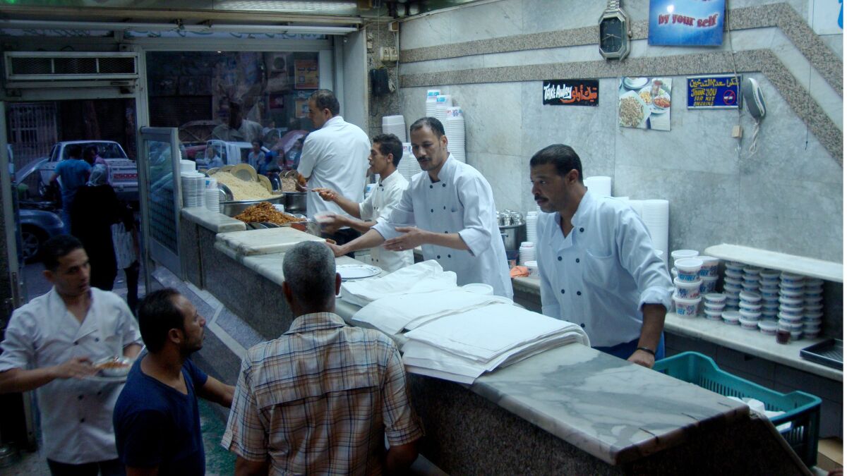 Cooks assemble koshary, classic Egyptian takeout, at Koshary Abou Tarek in downtown Cairo. Price increases of staples such as sugar, rice and wheat have made it more expensive to buy and even make koshary at home, diners say.