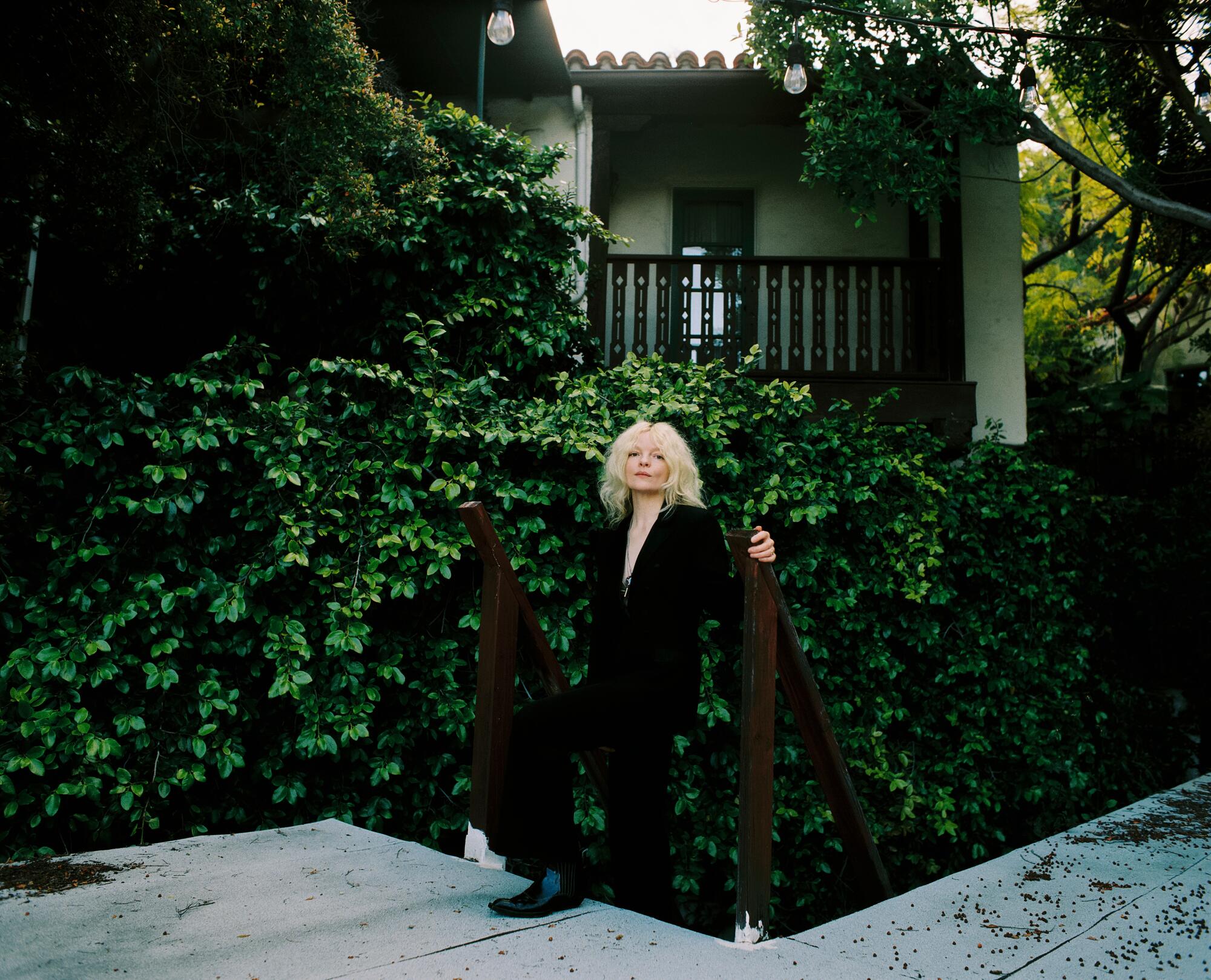 Jessica Pratt stands in front of a greenery-covered fence at the In Sheep's Clothing HQ.