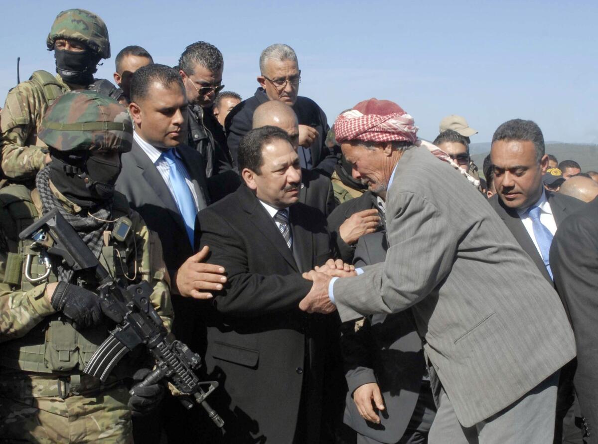 Tunisian Interior Minister Lotfi Ben Jeddou, center, greets the father of Abdelhamid Ghazouani, one of two policemen killed by militants, during his funeral in Jendouba on Feb. 17, 2014.