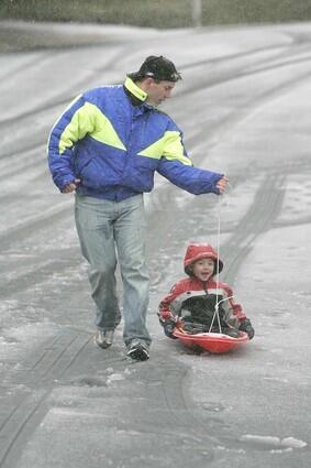 Jeff Boyer gives his son Sean, 4, a ride on a sled down hail-covered Willow Haven Drive in front of their home in La Crescenta.
