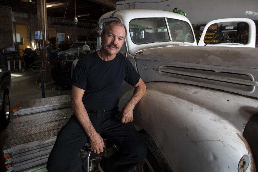 LOS ANGELES, CALIF. - NOVEMBER 01: Portrait of Greg "Gadget" Abbott, car inventor and EV whiz in his shop in Los Angeles, Calif. on Friday, Nov. 1, 2019. He converts retro sports cars to electric power. He is sitting next to his 1947 Ford truck and a Tesla car batteries. (Francine Orr / Los Angeles Times)