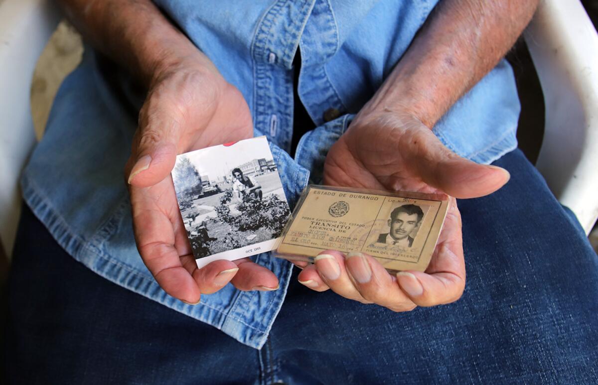 A man's hands hold a photo and a driver's license