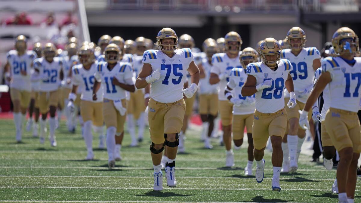 UCLA players run on the field before the Bruins' 14-7 loss to Utah at Rice-Eccles Stadium.