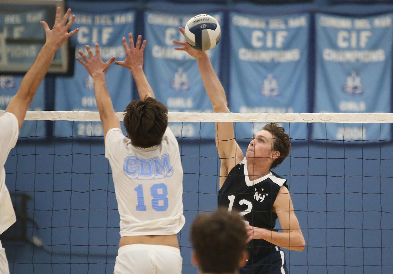 Newport Harbor's Dayne Chalmers (12) puts a kill past Corona Del Mar blocker Bryce Dvorak (18) during second round of the Battle of the Bay boys' volleyball match in Surf League play on Wednesday.