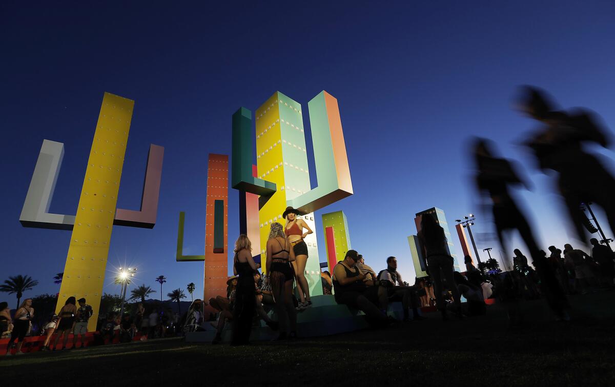 Festival goers hang out around "Colossal Cacti" as night falls on Day 1 of the Coachella Music and Arts Festival.