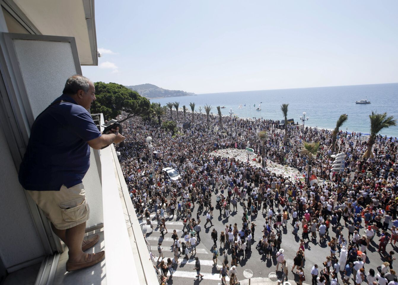 Ghassan Zaour watches people gathered around a makeshift memorial after observing a minute of silence to honor the victims of deadly attack on the Promenade des Anglais in Nice.