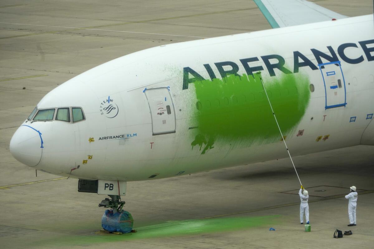 Activistas de la agrupación ecologista pintan el costado de un Boeing 777 de Air France 