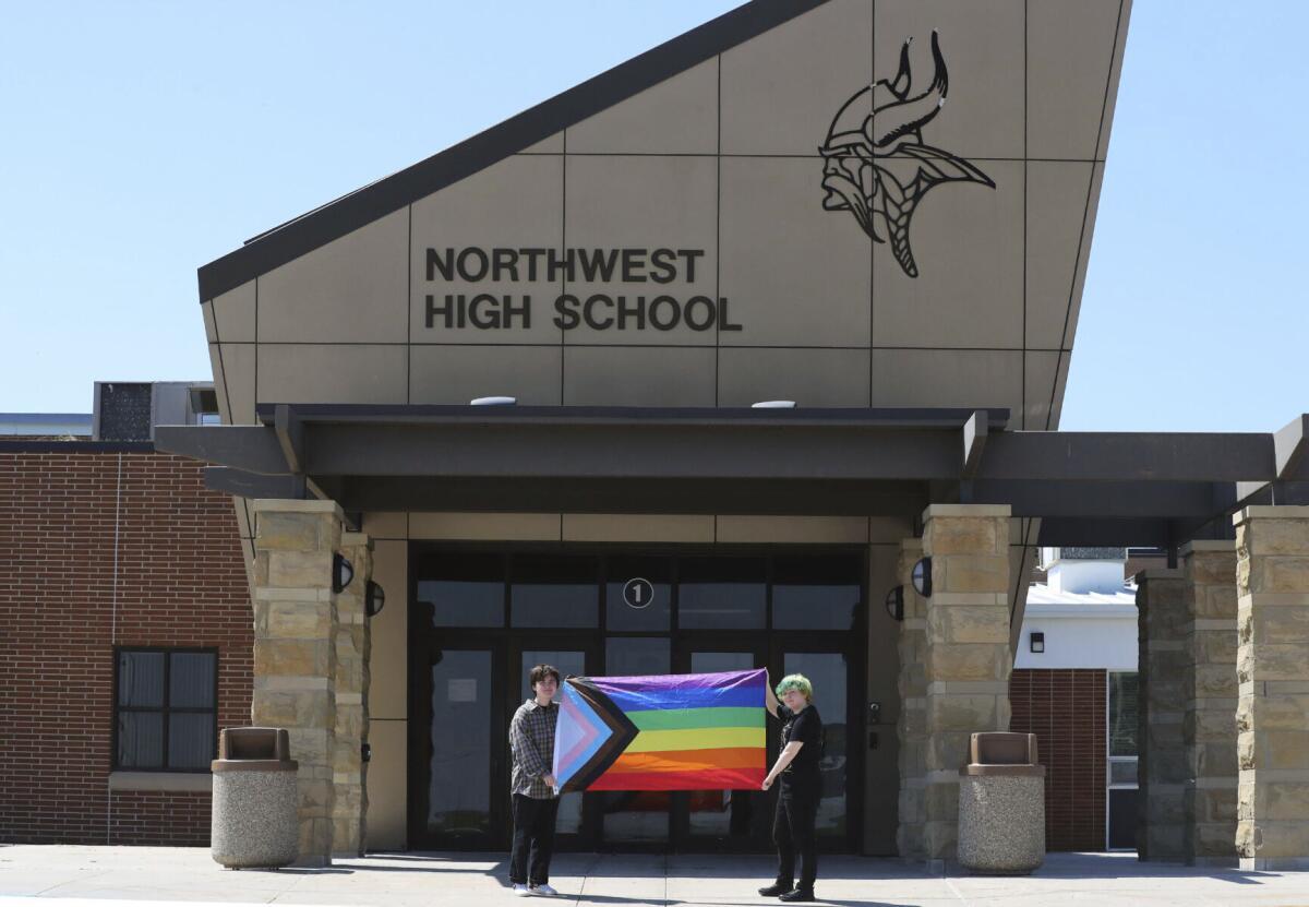 Students holding Pride flag outside school entrance