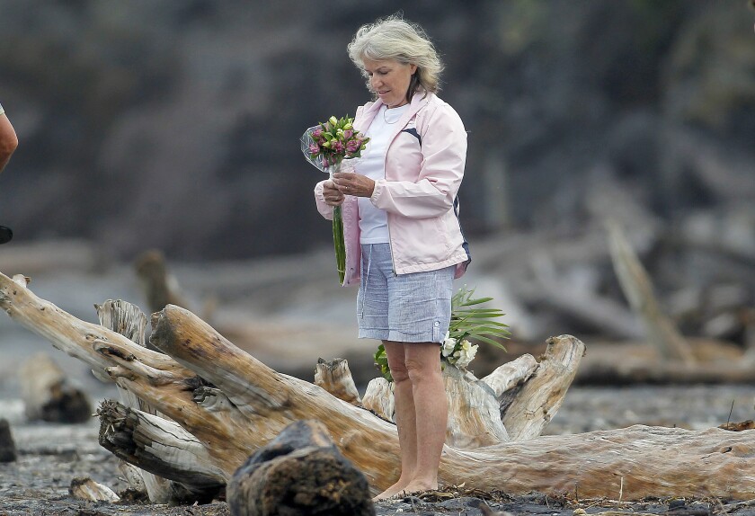 A woman prepares to lay flowers on a beach following a shark attack at Bowentown near Waihi in New Zealand, Friday, Jan 8, 2021. A woman has died Thursday, Jan. 7, in what appears to be New Zealand's first fatal shark attack in eight years, police say. (George Novak/Bay of Plenty Times via AP)