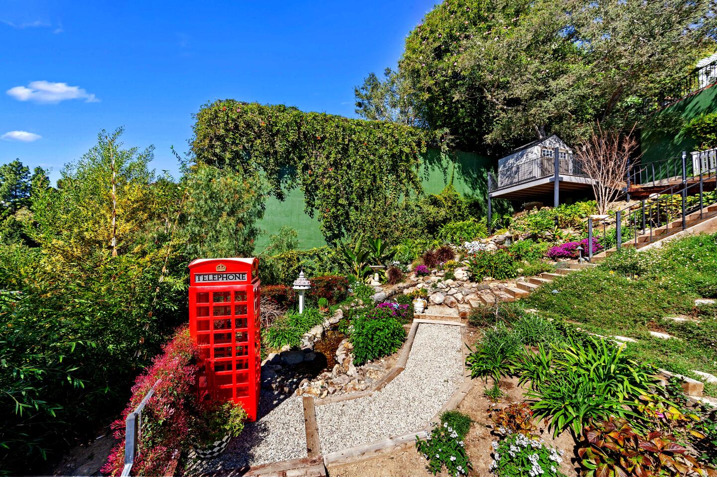 Nigel Lythgoe's property overlooks the Bel-Air Country Club golf course. It includes a 1930s residence and a two-story guesthouse. The verdant backyard has tiered gardens and a bright red phone booth.