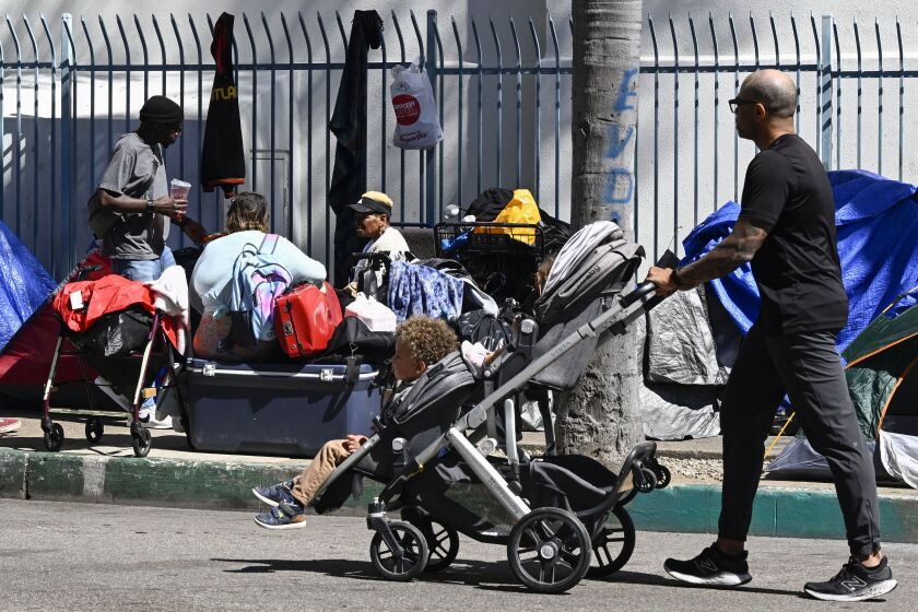 Jarvis Leverson pushes his children Jordan, 1 1/2, and Jetson, 3, past a homeless encampment in downtown San Diego Mar. 9, 2023 in San Diego. The encampment is four blocks from his home. (Photo by Denis Poroy)