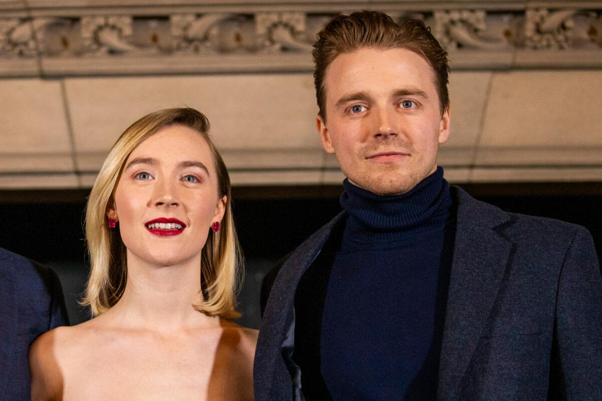 Saoirse Ronan in a neutral-colored gown and Jack Lowden in black turtleneck and dark jacket.