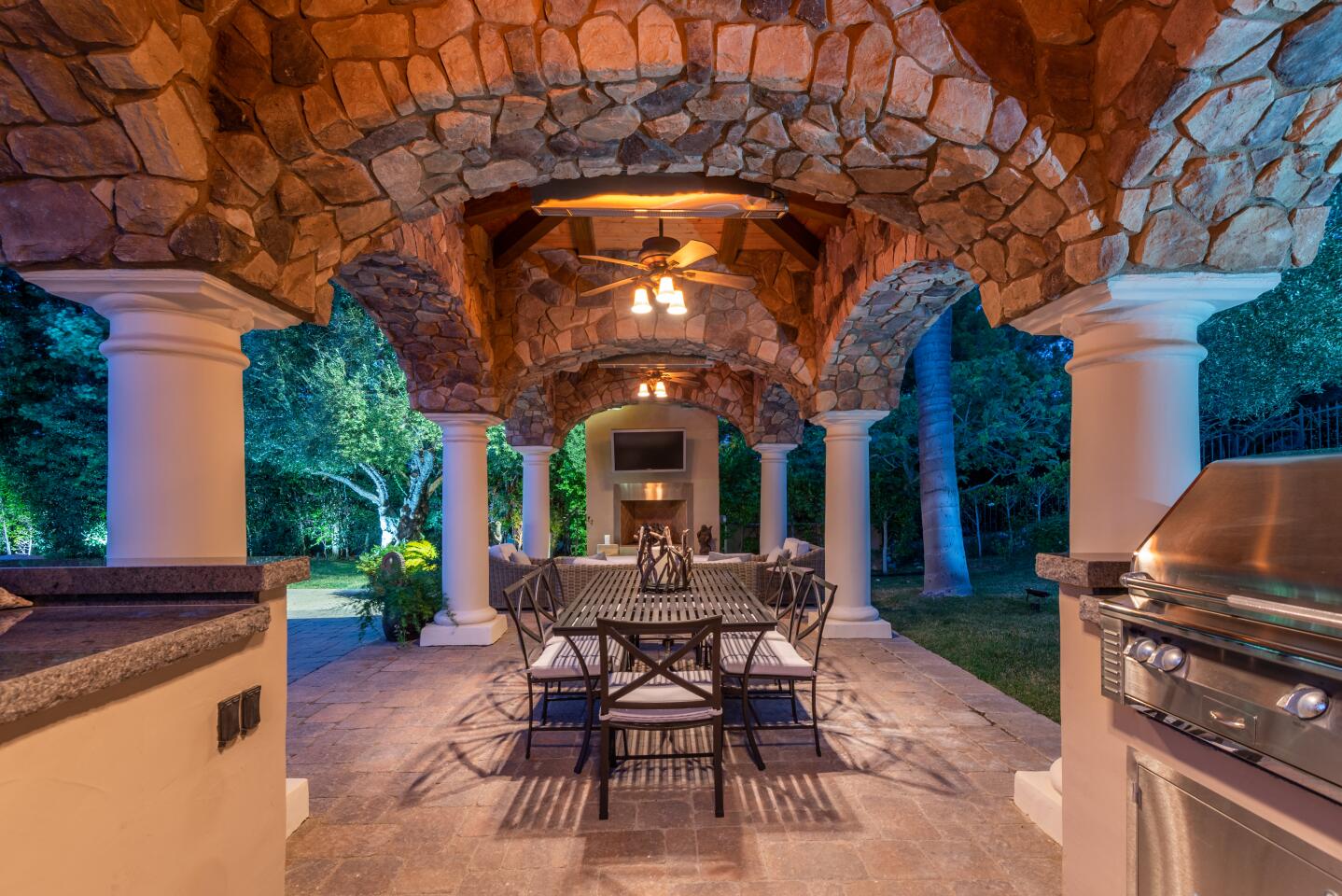 There are multiple outdoor living spaces, including a stone-clad dining pavilion with an outdoor kitchen.