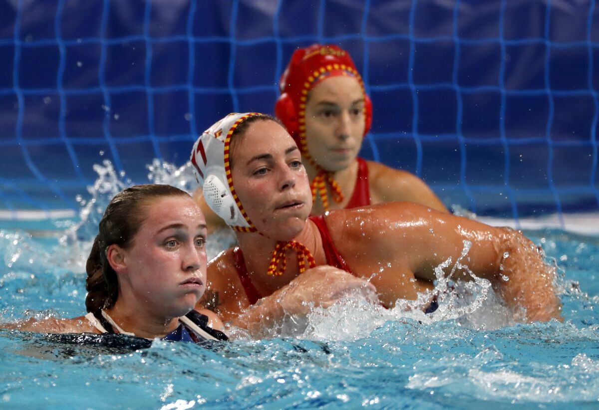 A U.S. women's water polo player in the pool beside two Spanish competitors.