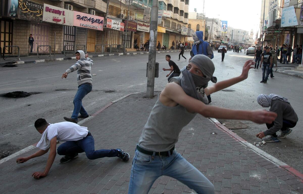 Palestinian protestors throw stones at Israeli security forces during clashes Friday in Hebron on the West Bank.