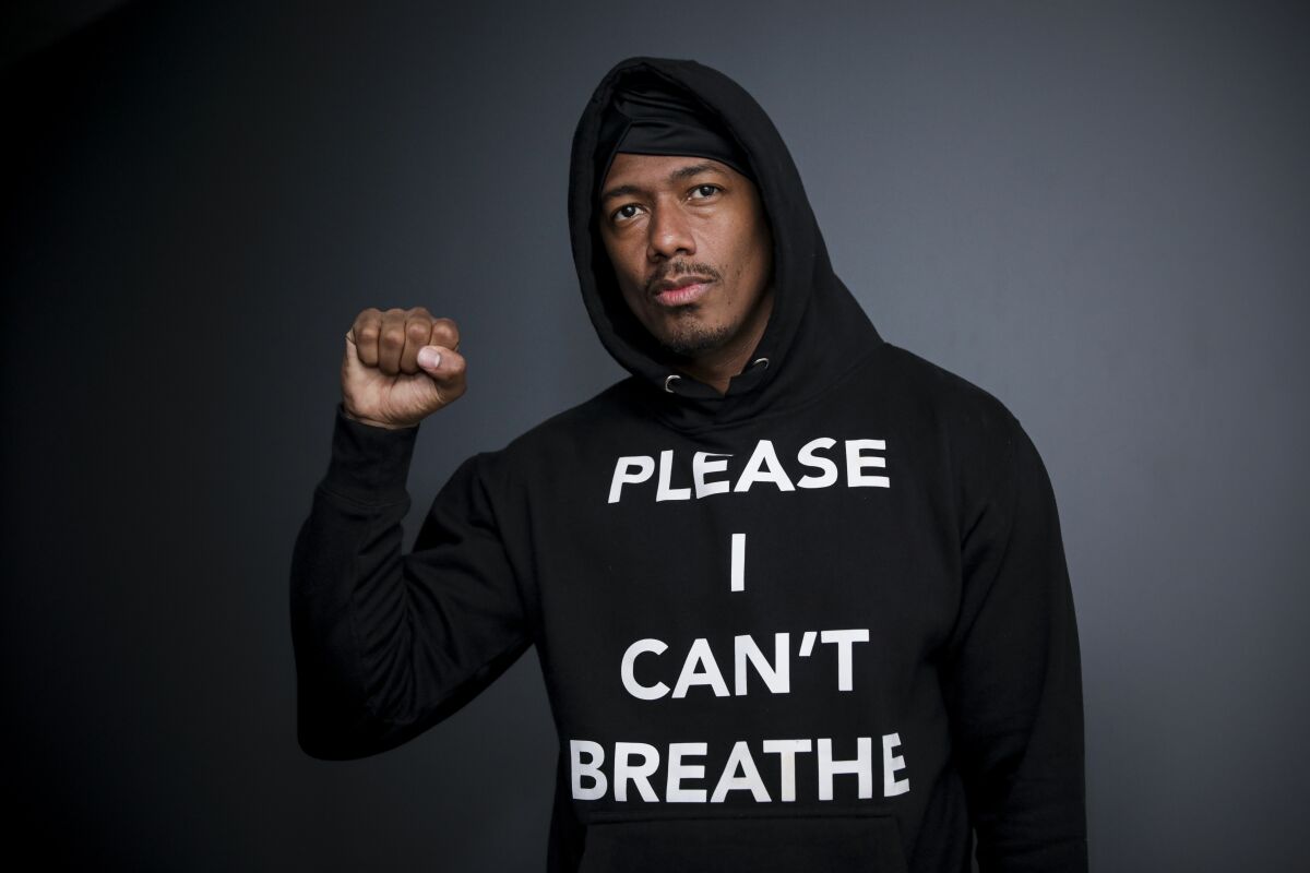 Nick Cannon raises his fist and wears a black hoodie that says "Please I Can't Breathe."