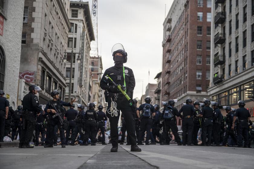 Los Angeles, CA, Tuesday, June 2, 2020 - LAPD officer Decote watches for people tossing debris from tall buildings as dozens of protesters are arrested for curfew violations on Broadway. (Robert Gauthier / Los Angeles Times)