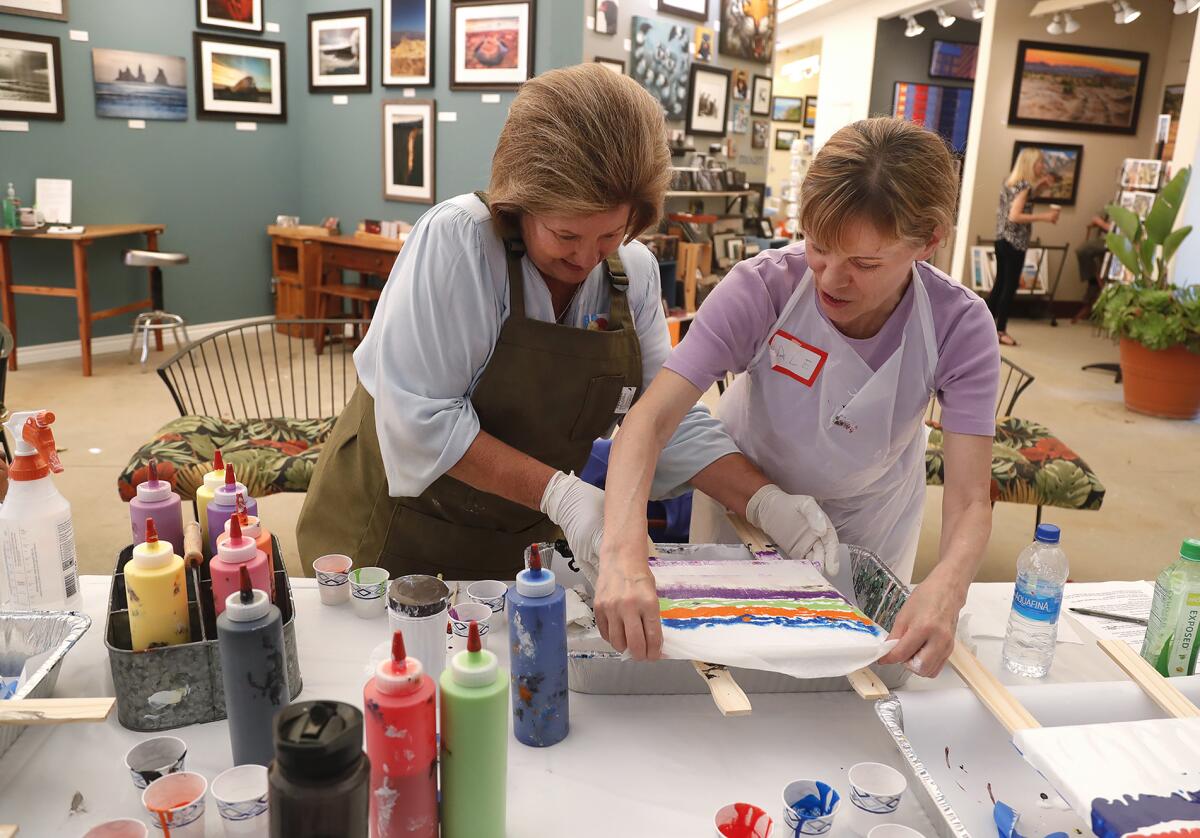 Art instructor and water colorist Emilee Reed helps a participant during a "pour paint" workshop at the Laguna Art-A-Fair.