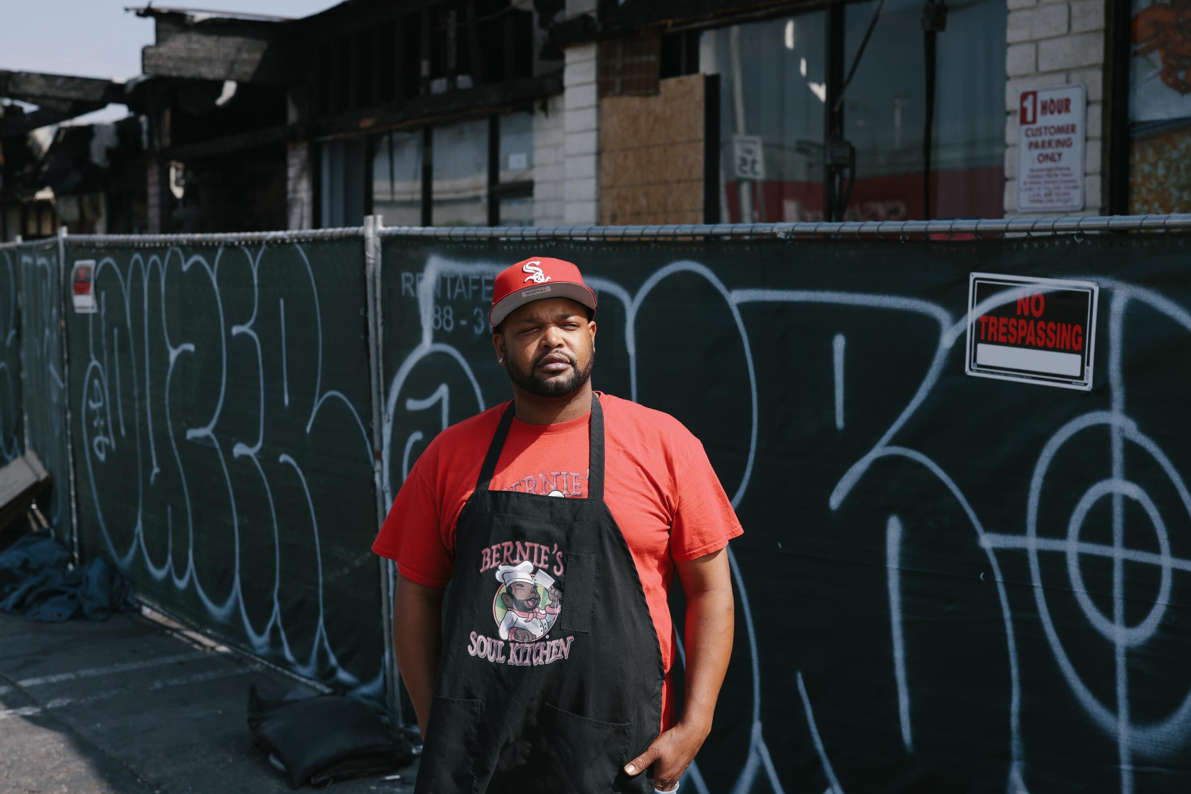 A man stands in front of a restaurant blocked by fencing.