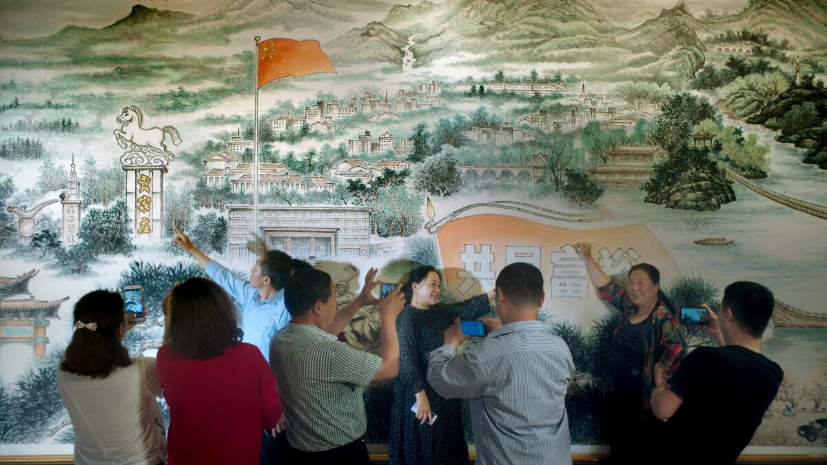 People point at a mural while bystanders snap photos.