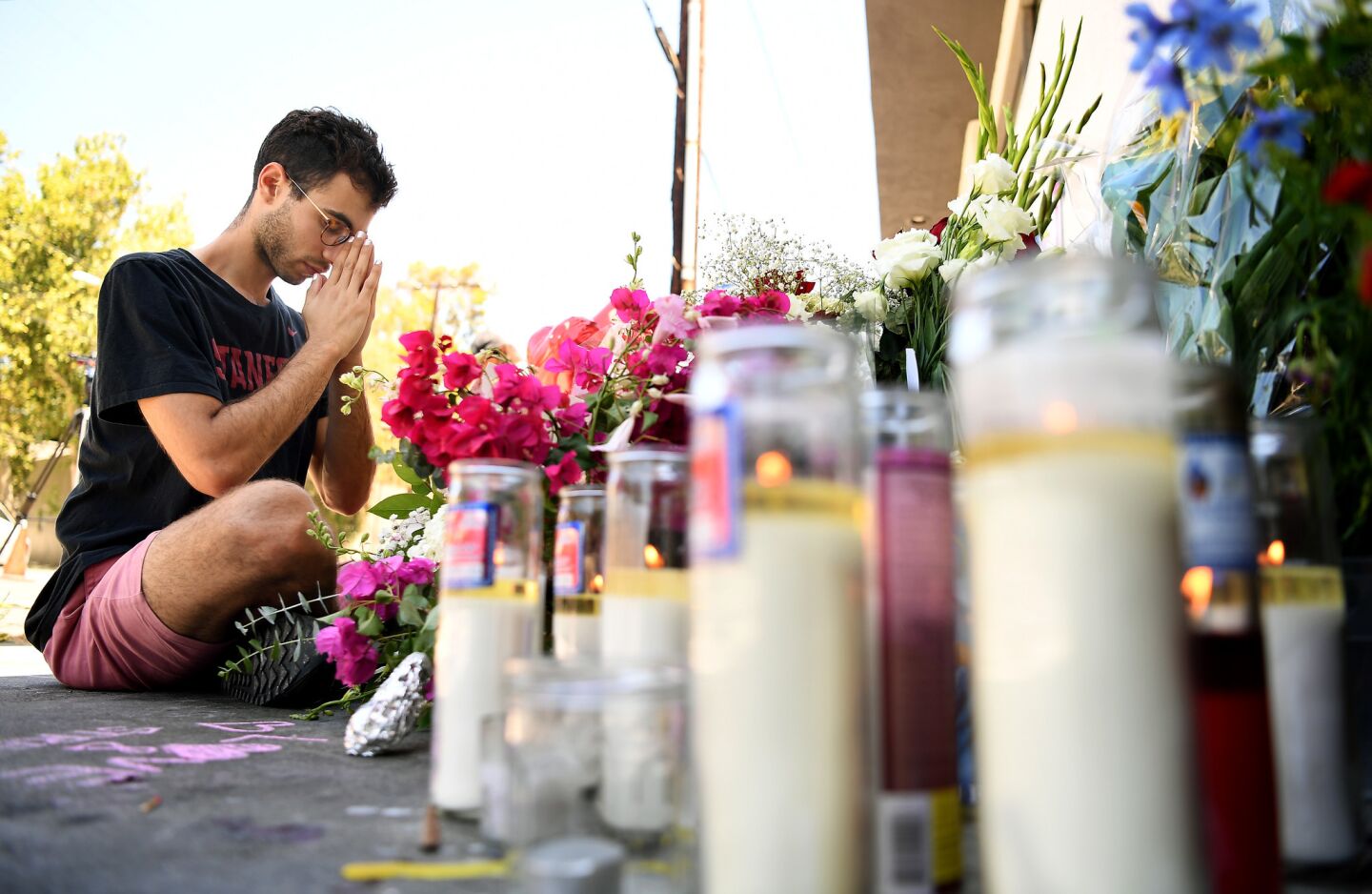 Paolo Singer, 27, of Silver Lake prays at a memorial outside of Trader Joe's in Silver Lake, where a shooting left one woman dead and at least two wounded Saturday.