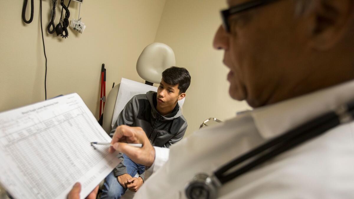 Dr. Karunyan Arulanantham, right, talks with a patient at the Antelope Valley Community Clinic.