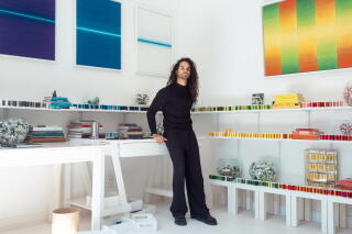 A man in black clothing stands in an art gallery.
