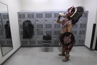 Richard Guzman, 19, a San Diego State sophomore, practices blowing his conch shell as gets ready to be the SDSU Aztec Warrior mascot while in a men's room.