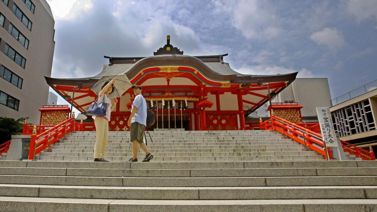 A couple chats in front of the main hall of Hanazono Shrine in Tokyo. A round-trip fare from mid-August to early December puts Japan's capital within reach.