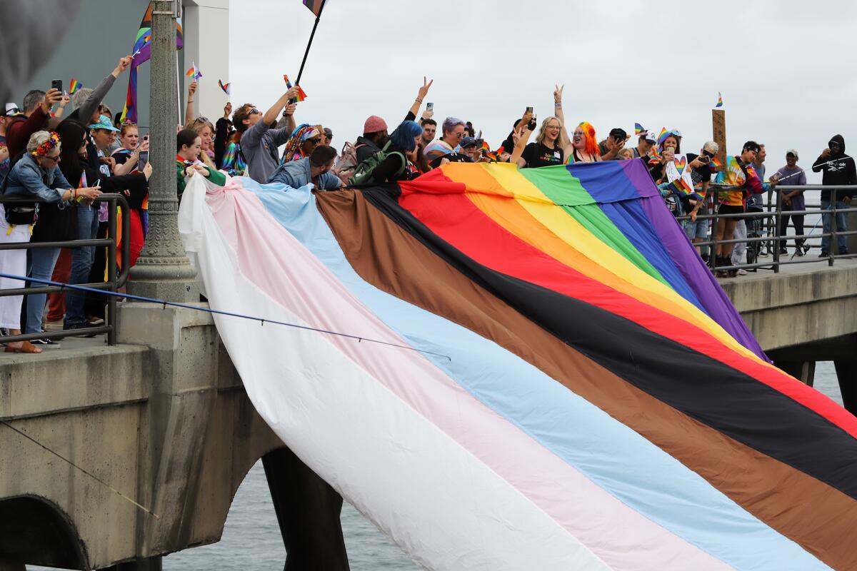 Supporters cheer as a giant Pride flag is displayed on Huntington Beach Pier.