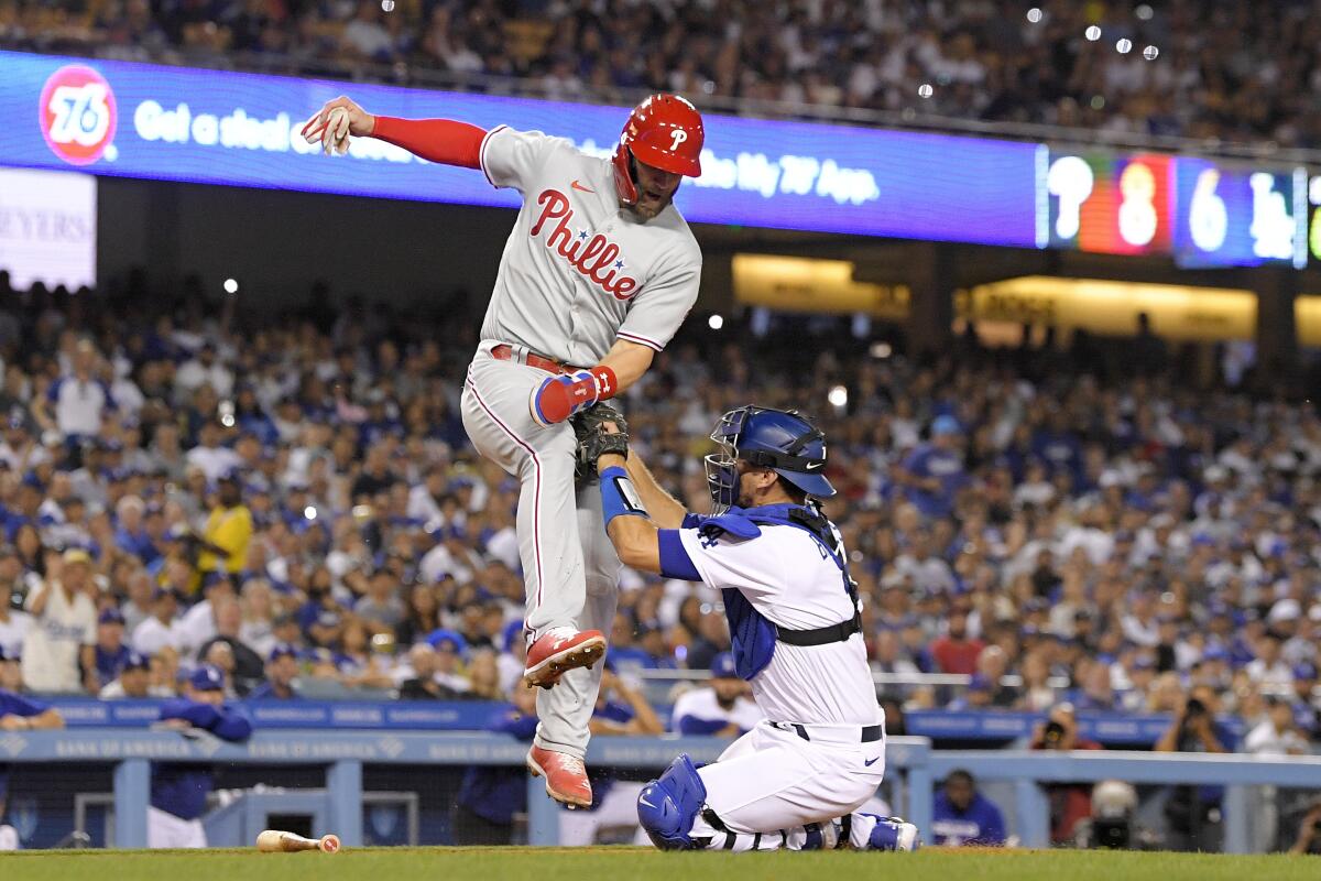 Philadelphia Phillies' Bryce Harper (3) high fives Trea Turner, right,  after scoring on an RBI-single hit by Bryson Stott during the third inning  of a baseball game against the Los Angeles Dodgers