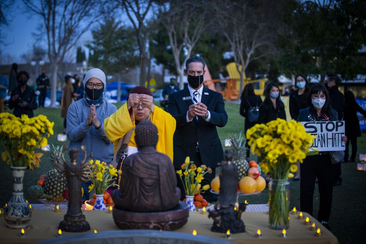 People pray before a figure of the Buddha