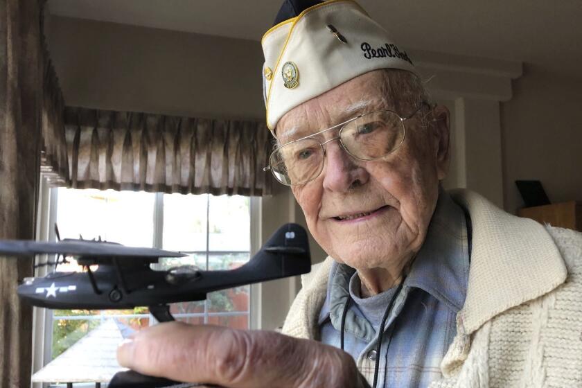 Retired U.S. Navy Cmdr. Don Long holds up a replica of the military seaplane he was standing watch on when Japanese warplanes attacked Hawaii 77 years ago, Friday, Dec. 7, 2018 at his home in Napa, California. Long was alone on the anchored plane in the middle of Kaneohe Bay, across the island from Pearl Harbor, when the attack happened, watching from afar as the bombs and bullets killed and wounded thousands. When the gunfire finally reached his plane, setting the aircraft ablaze, he jumped into the water and found himself swimming through fire to safety. (AP Photo/Eric Risberg)