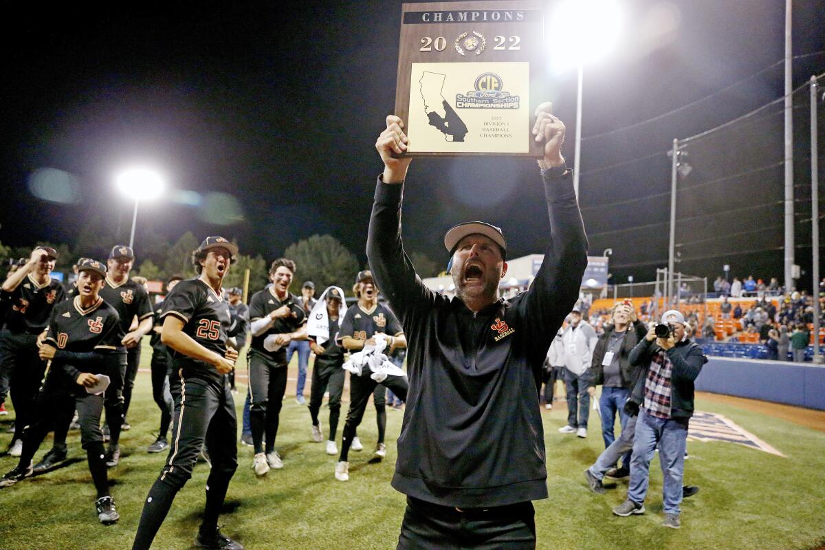 JSerra coach Brett Kay holds up the CIF Southern Section Division 1 championship plaque after the Lions' win.