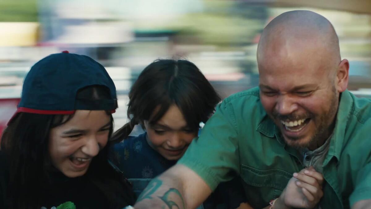 A man and two kids laugh on a spinning ride.