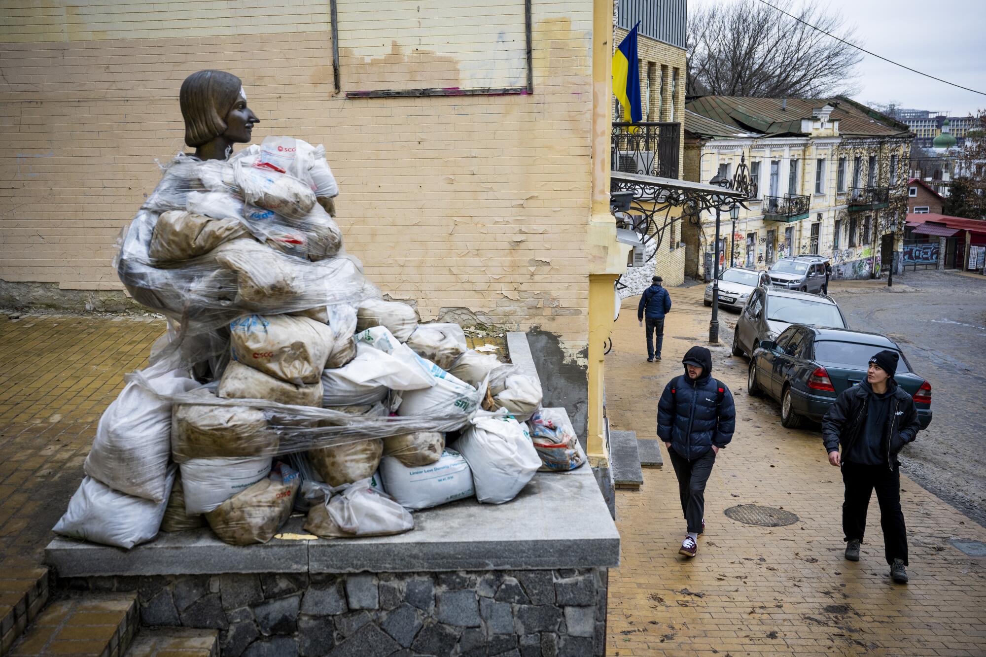 A statue is almost entirely covered by sandbags with just the head sticking out.