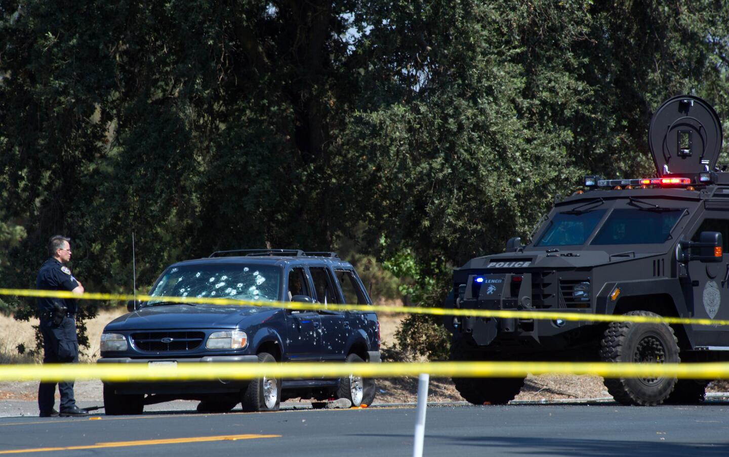 A Stockton police officer investigates the scene after a vehicle involved in a suspected bank robbery was stopped in the Northern California city. Three women were taken hostage by the alleged robbers; two were shot and thrown or leaped from the getaway vehicle, the other was killed.