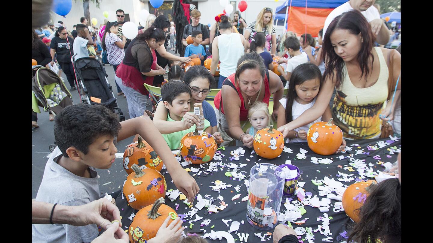 Its a messy affair as kids and their parents decorate pumpkins during Torelli Realty's annual pumpkin patch and Halloween party on Thursday night in Costa Mesa.