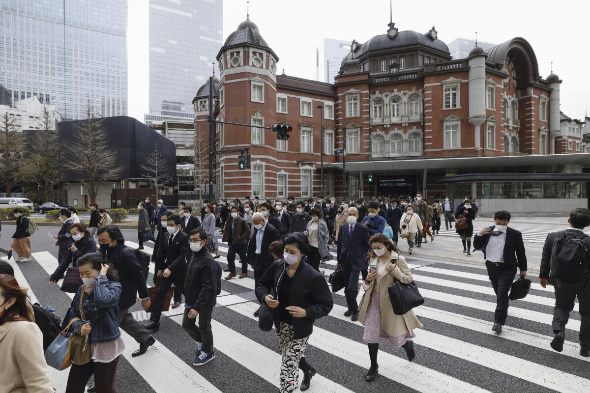 People walk across an intersection near Tokyo Station in Tokyo on Monday, March 13, 2023. 
