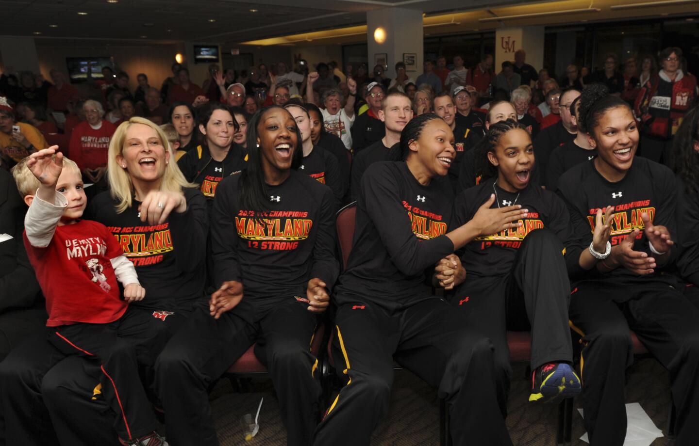 University of Maryland Women's basketball team cheer as they learn their seed and their opponent (Navy) in the NCAA tournament from one of the ESPN channels. From left are Coach Brenda Frese holding Tyler, one of her twins; players Laurin Mincy (#1); Alicia DeVaughn (#13); Sequoia Austin (#0); and Alyssa Thomas (#25).