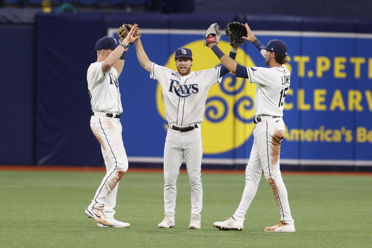 Tampa Bay Rays right fielder Brett Phillips, center, celebrates with teammates Luke Raley, left, and Josh Lowe after defeating the Boston Red Sox in a baseball game Monday, July 11, 2022, in St. Petersburg, Fla. (AP Photo/Scott Audette)