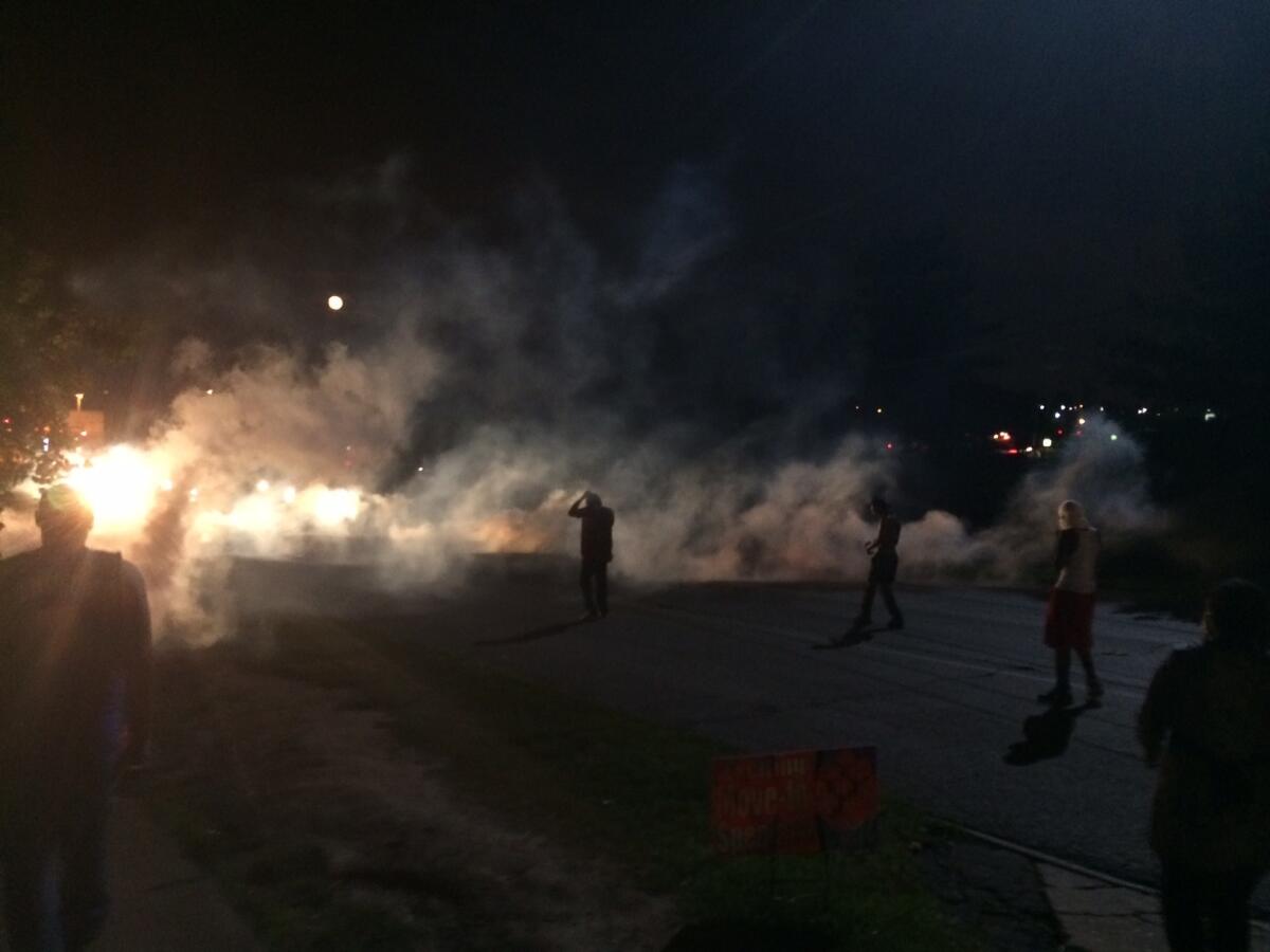 Demonstrators in Ferguson, Mo., scatter Monday night after police fired tear gas.