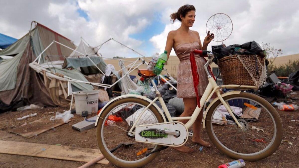 Morgan Gallerito wears a glamorous dress and holds a homemade dream catcher while being evicted from a large homeless encampment along the Santa Ana River trail Friday.