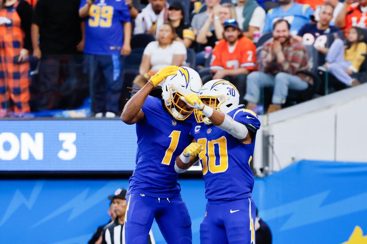 The Chargers' Austin Ekeler (30) celebrates with Quentin Johnston (1) after scoring a touchdown against the  Broncos.